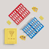 Two “Guess Who?” game boards—one red, one blue—sit on a light surface with yellow Mystery Cards and the yellow Board Game: Guess Who? Vintage Bookshelf Edition box displaying the title on the cover.