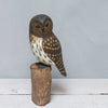 The Hand Carved Ornament - Barred Owl - 13"H features detailed feather carvings and brown, white, and tan paint, perched on a cylindrical wooden base against a plain gray background.