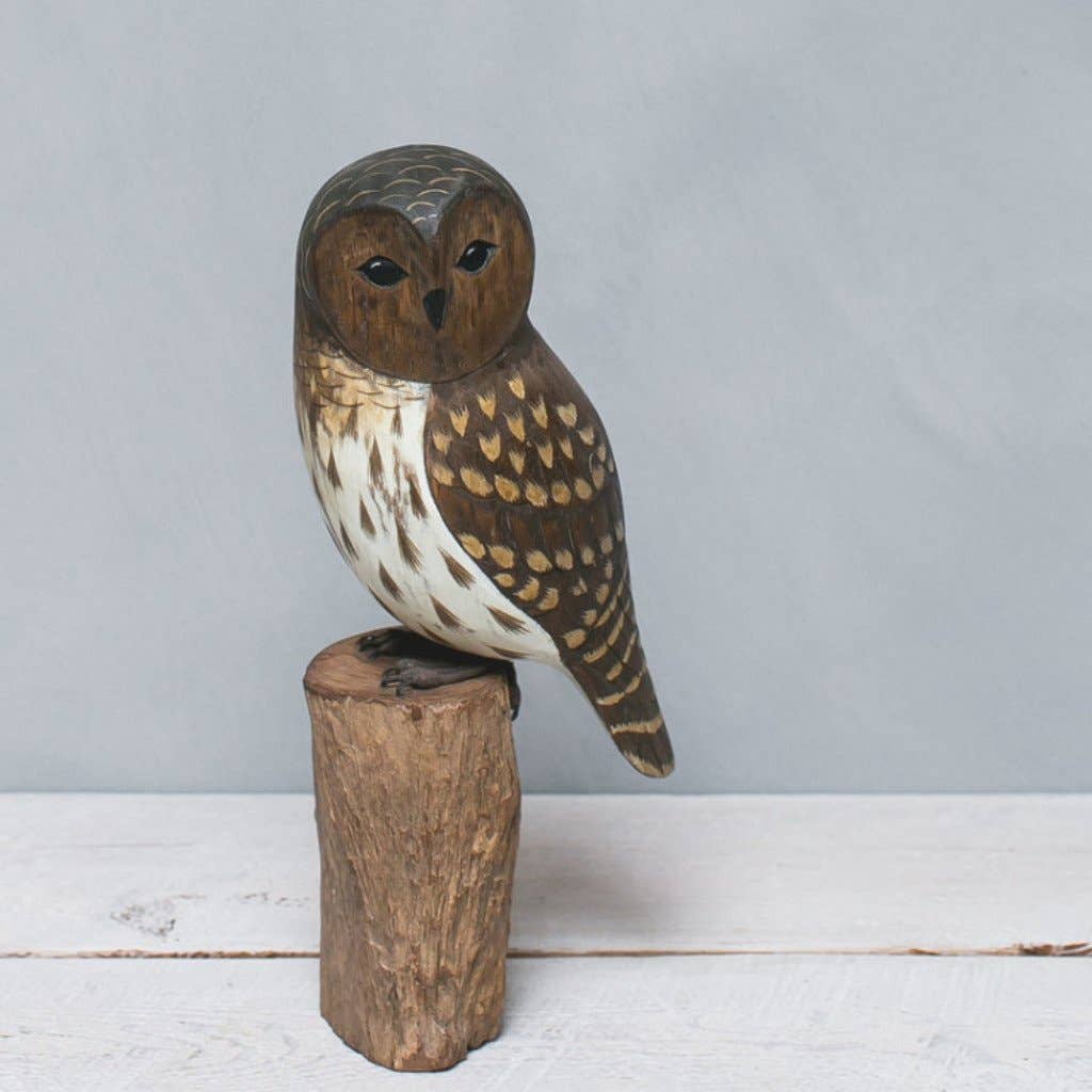 The Hand Carved Ornament - Barred Owl - 13"H features detailed feather carvings and brown, white, and tan paint, perched on a cylindrical wooden base against a plain gray background.