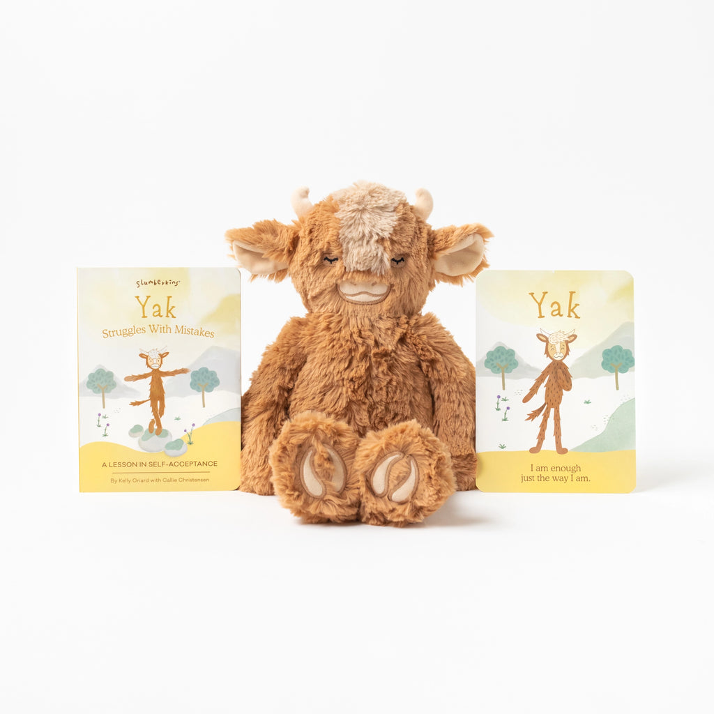 A Slumberkins Yak Kin + Lesson Book On Self Acceptance centered between two children's books titled "Yak Struggles with Mistakes" and featuring illustrations of a yak on the covers. The books are about learning to accept themselves.