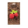 The Valery the Raspberry Teething Toy, shaped like two red raspberries with green leaves, is an eco-friendly sensory teether made from natural rubber and sold on a fruit-themed cardboard backing labeled “Oli & Carol.”.