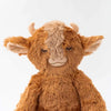 A Slumberkins Yak Kin + Lesson Book On Self Acceptance, resembling a happy brown cow with soft fur, prominent ears, and small horns, smiling gently against a plain white background, symbolizes learning to accept themselves.