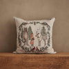 Coral & Tusk Christmas Cheer Wreath Pillow, a square embroidered linen pillow featuring a bear, a fox, and a reindeer standing inside a Christmas wreath decorated with pinecones and cardinals.