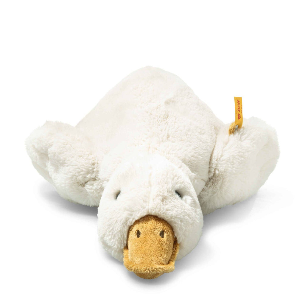 The Steiff XL Gilda Goose is a plush stuffed animal with a soft white body and beige beak, lying flat with wings and legs spread out. A small yellow tag is attached, making it a perfect huggable toy for cozy moments.
