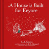 Red book cover titled "Winnie-the-Pooh: A House is Built for Eeyore," a classic picture book by A.A. Milne with E.H. Shepard illustrations. Winnie the Pooh, Piglet, and Eeyore stand near a stick house below the title.
