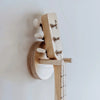 Close-up of a Guitar Wall Hanger for Loog Mini holding the neck of a Loog Pro guitar. The image emphasizes the tuning pegs and part of the fretboard against a plain white background, highlighting the sleek design intended for convenient storage.