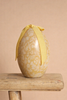 The Easter Basket Gift Set, featuring a decorative yellow egg with a floral pattern and a yellow ribbon bow, is displayed on a wooden stool against a plain beige background.