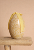The Maileg Easter Egg With Chick is a decorative cream yellow egg with a floral pattern and a yellow ribbon bow, displayed on a wooden stool against a beige background.