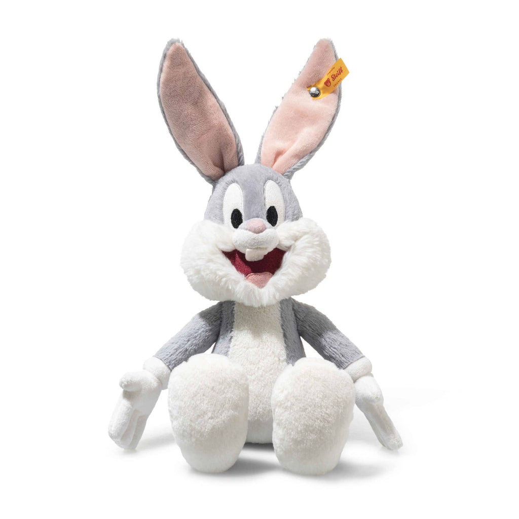The Steiff Looney Tunes Bugs Bunny plush, featuring gray and white fur, big ears, a pink mouth, and the signature Steiff Button in Ear tag, sits upright against a white background—a perfect collectible for fans.