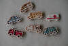 A photo of seven colorful service vehicle cookie cutters from the Service Vehicle Cutter Set - Eco Playdough Tool displayed on a white surface, featuring shapes like a police car, fire truck, ambulance, school bus, tow truck, and two more emergency vehicles. This transport-themed set is perfect for eco playdough activities and sensory play.