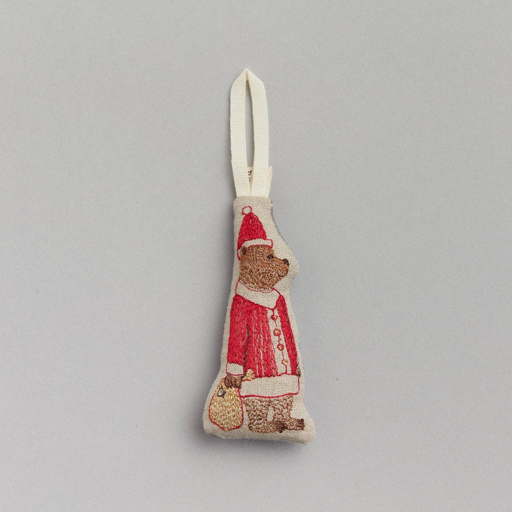 The Santa Bear Ornament, adorned in a festive red suit with a hat and sack, brings an elegant touch to holiday decor. It features a cream loop for easy hanging and makes an ideal Christmas gift. Displayed against a light gray background, it beautifully captures the spirit of the season.