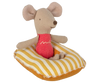 A small fabric toy mouse with beige fur is seated on a Maileg Beach Raft, Small Mouse - Yellow Stripe. The mouse is wearing a red shirt with the word "mail" embroidered on it. The mouse's features are simple, with black eyes, a stitched smile, and large rounded ears like those of baby mice.