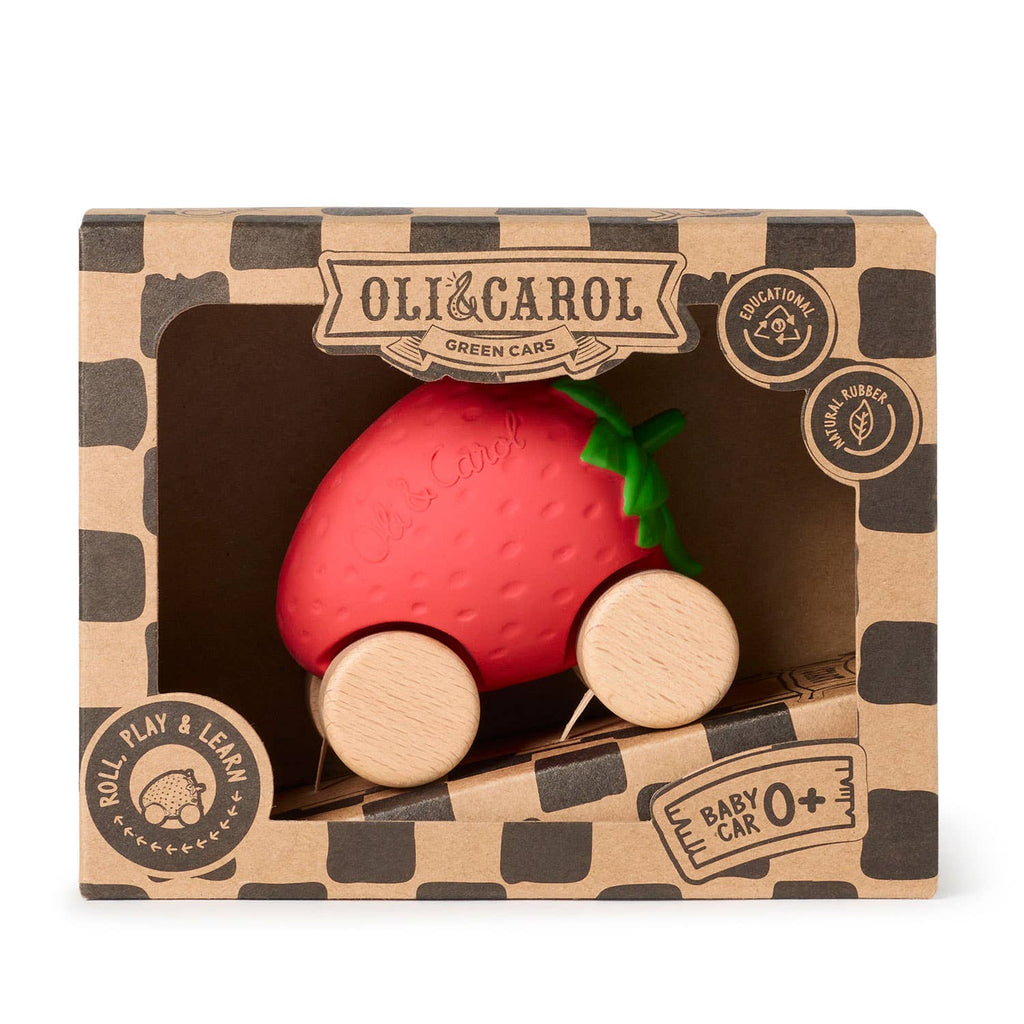 Sweetie The Strawberry Baby Car is an eco-friendly, red strawberry-shaped toy with green leaves and wooden wheels. Made from natural rubber, it comes in a brown "Oli & Carol Green Cars" box labeled for babies 0+.