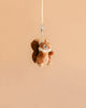 The Bukowski - Brunis Squirrel Bag Charm, a small plush woodland companion, dangles from its beige strap against a simple light brown background.