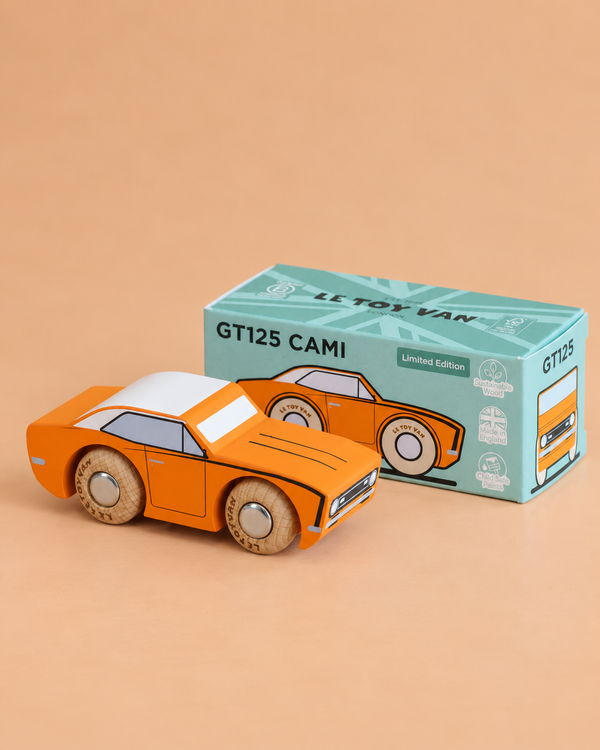 A wooden racing car in orange and white sits in front of its teal box labeled “No. 22 GT125 Cami | Made in England.” The box features illustrations and the words “Limited Edition.” Reminiscent of classic American muscle, this striking toy racing car stands out against the beige background.