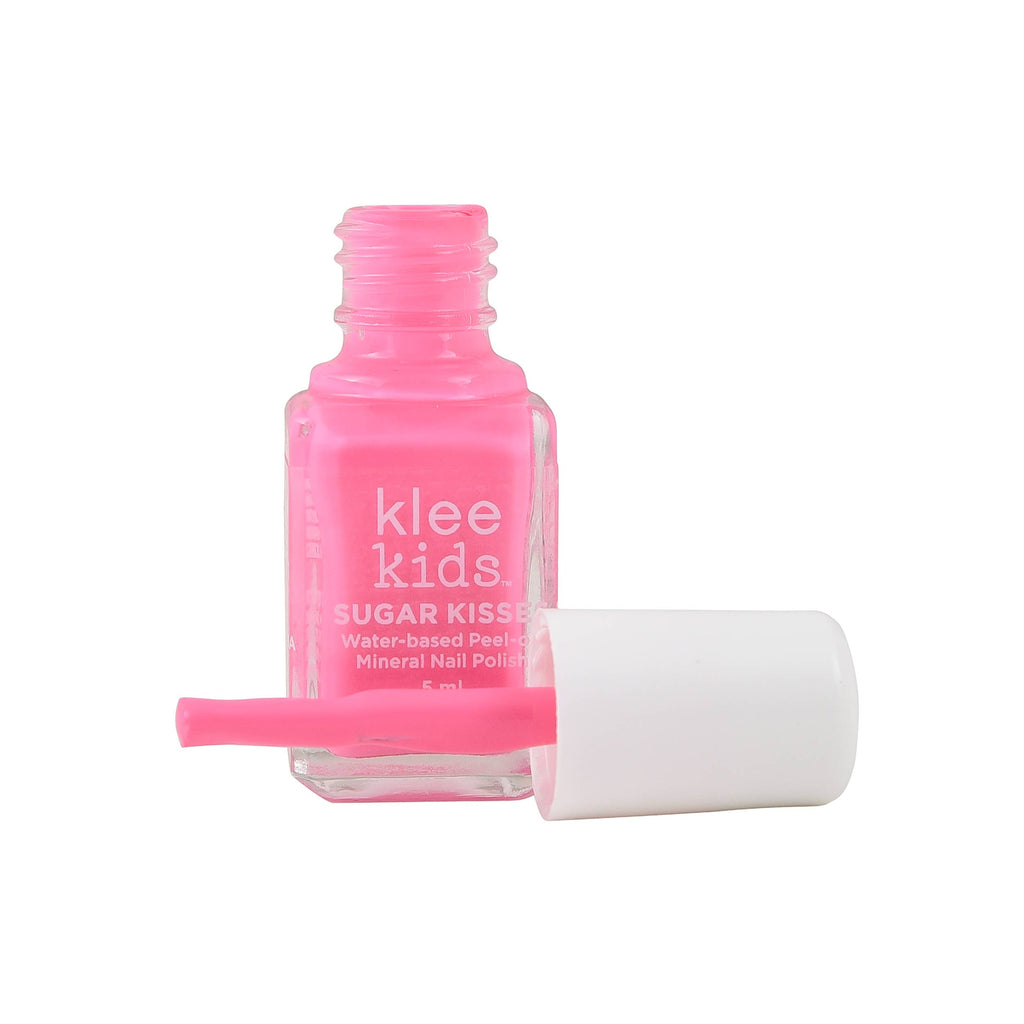 An open bottle of Klee Naturals Deluxe Makeup Kit - Pink Ballet Fairy, featuring bright pink, non-toxic nail polish with a white cap and applicator brush lying in front.
