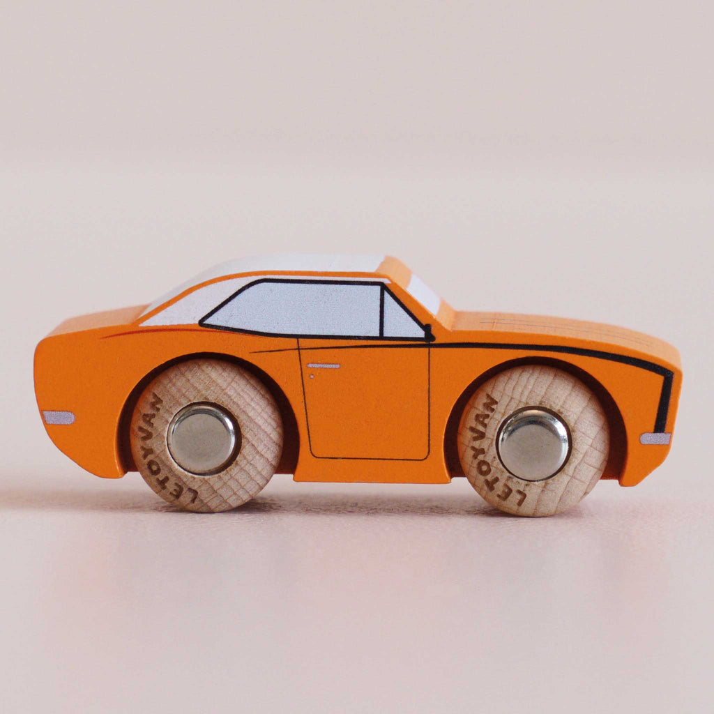 No. 22 GT125 Cami, a small orange wooden racing car toy with black detailing and round wooden wheels, made in England, sits on a light surface and is viewed from the side.