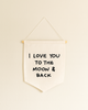 The I Love You To The Moon And Back Canvas Sign is a white fabric wall banner on a wooden dowel with bold black lettering—ideal handmade wall decor or artisan gift.