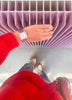 A person in a red sweater and striped pants stands on a gray floor, beige shoes on, their hand—with a Mini Kyomo Watch - Lavender Field—resting on a lavender radiator.