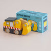 A wooden excavator with yellow and black details sits in front of its blue box labeled “No. 37 GT210 Eddie | Made in England.” Perfect as a construction toy, the box displays an illustration that matches the toy.