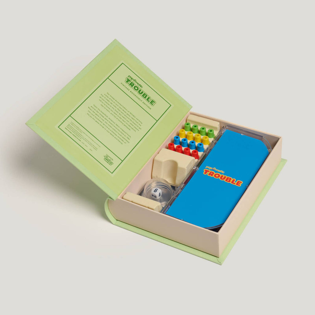 The Board Game: Trouble Vintage Bookshelf Edition features an open game board with colorful pegs, a clear Pop-O-Matic die roller, and blue surface, all organized in a light green box with instructions inside the cover.