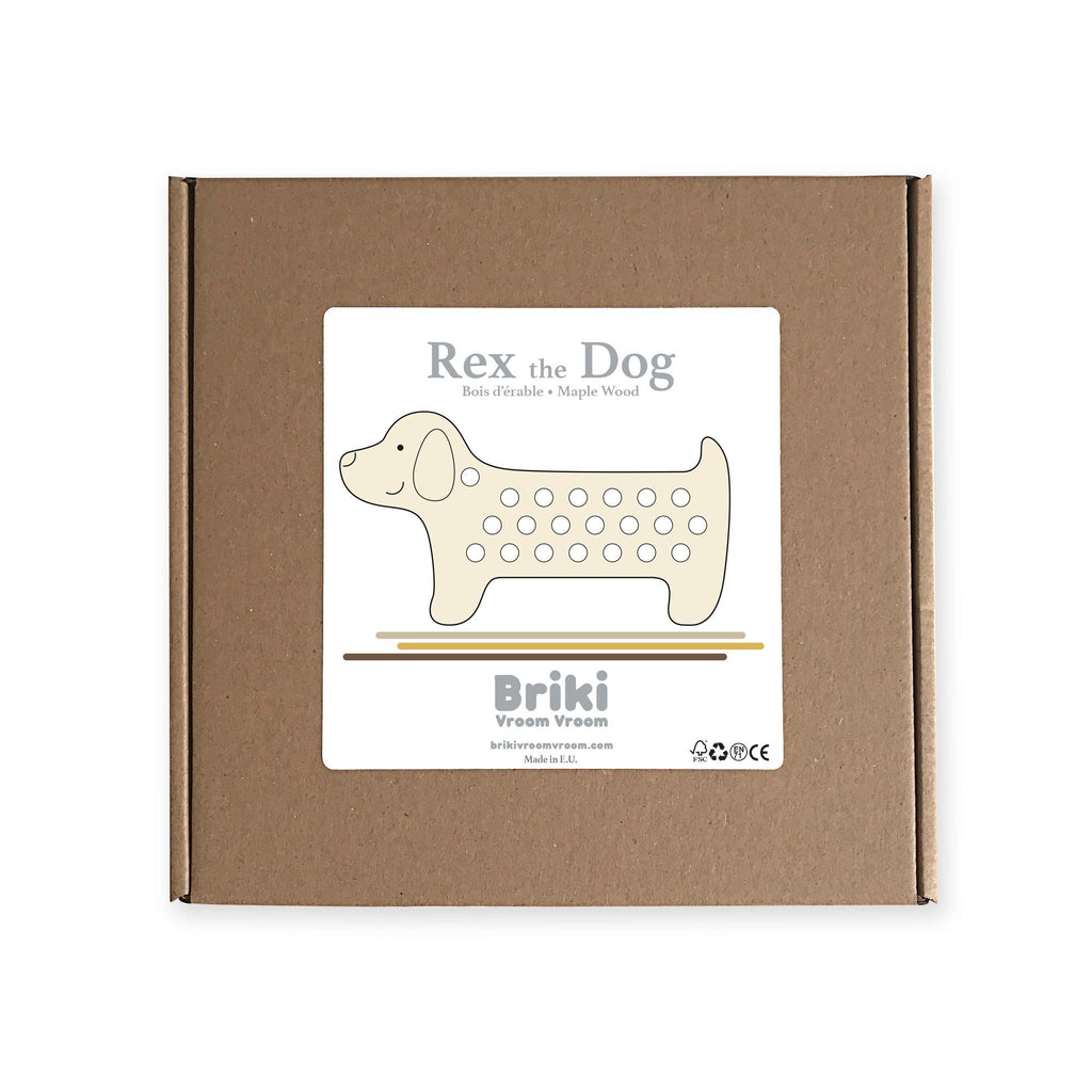 A brown cardboard box with a white label in the center. The label features an illustration of a wooden toy for children with polka dots, and text reads "Maple Wood Lacing Toy - Rex the Dog" and "Briki Vroom Vroom" along with contact information and small icons on the bottom.