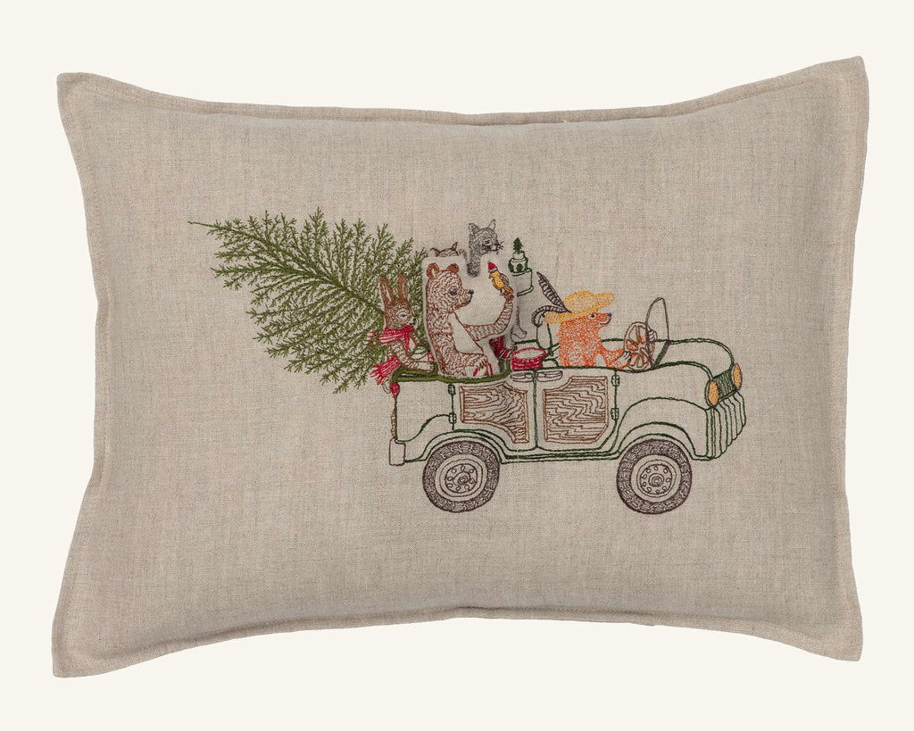 The Coral & Tusk Christmas Tree Car Pocket Pillow features woodland animals—fox, owl, raccoon, and bear—driving a car with a Christmas tree and gifts. Embroidered details add festive charm to this delightful holiday decor piece.