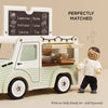 The Mobile Café Van is a pastel green, vintage-style toy with a chalkboard menu and two sweater-clad dolls for imaginative play. Made from FSC-certified wood. "Perfectly Matched with our Dolly Family Set – Sold Separately.