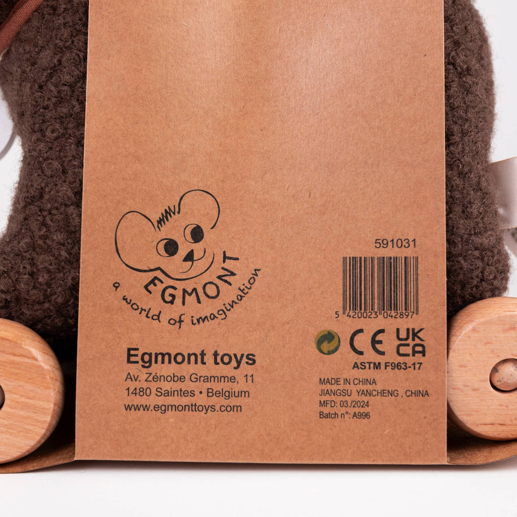 A tag attached to Pull-Along Raoul, a brown plush toy with natural wood wheels, displays the Egmont Toys logo, address, product information, certification marks, and a barcode.