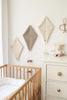 A serene nursery corner with a wooden crib featuring a white mattress, a white dresser adorned with a soft teddy kite, and Boucle Kite Wall Decor in taupe hanging on the wall. Scissors are mounted on the wall as decoration—children's room decor that invites imaginative play.