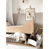 Cozy children’s bedroom with a light wooden bed, Senger Naturwelt Stuffed Animal - Large Brown Bear in a white toy cart, plush turtle, and wall decor with bunny, stars, and hot air balloon. Neutral beige and white GOTS-certified tones throughout.