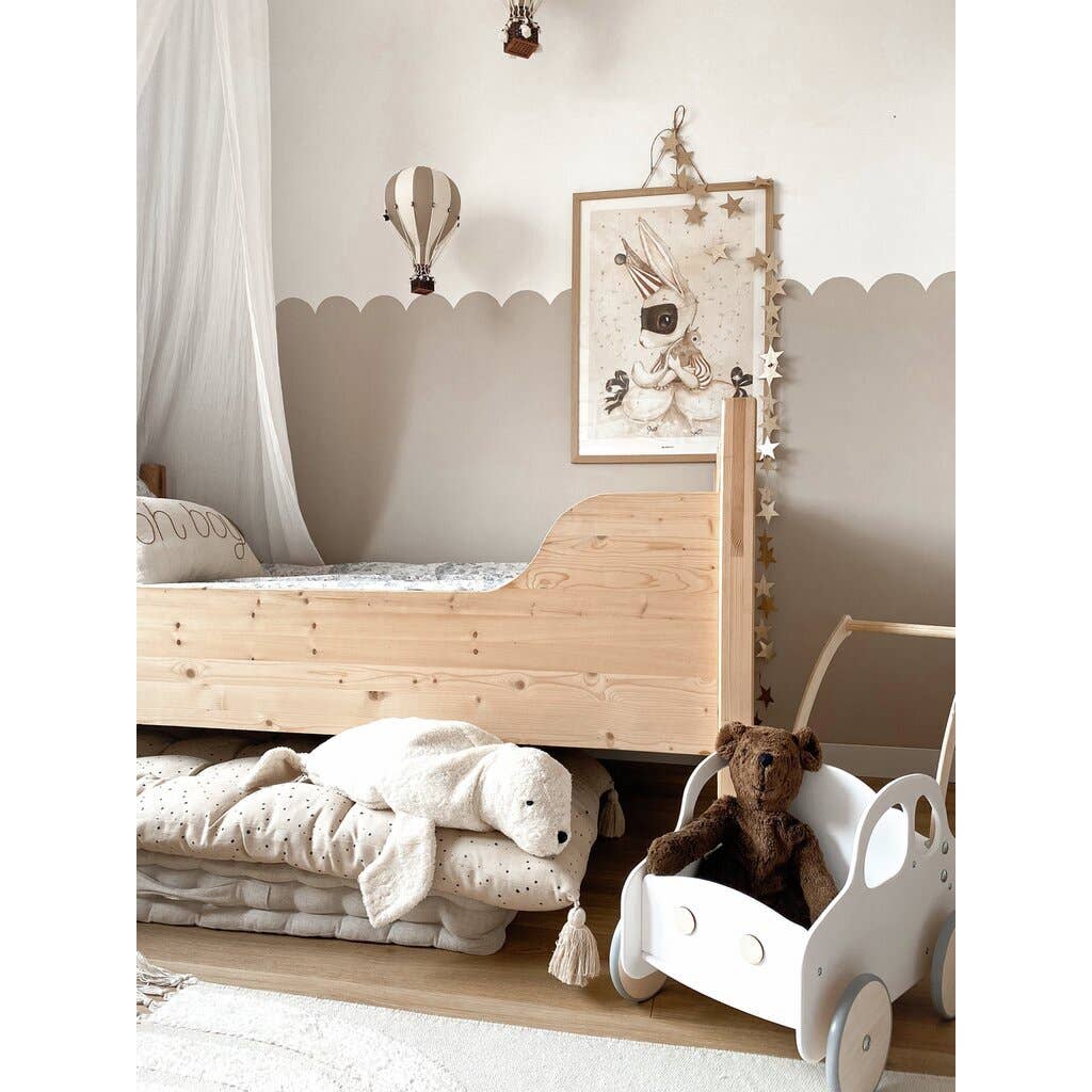 Cozy children’s bedroom with a light wooden bed, Senger Naturwelt Stuffed Animal - Large Brown Bear in a white toy cart, plush turtle, and wall decor with bunny, stars, and hot air balloon. Neutral beige and white GOTS-certified tones throughout.