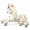 A Steiff, Starly Unicorn Plush Animal Toy, 28 Inches is shown lying down. The unicorn is white with a fluffy mane and tail, grey hooves, and a silver spiral horn on its forehead. It has black eyes and a gentle expression. Made from premium-grade woven plush, it wears a small tag on one of its ears.