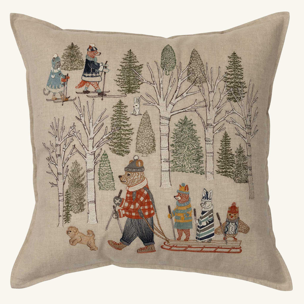 The Coral & Tusk Winter Fun Pillow showcases woodland animals and a small dog in winter attire, skiing and sledding among snowy trees, creating a playful and festive scene ideal for holiday decor.