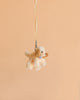 The Bukowski - Buddylina Dog Bag Charm features a small plush puppy with floppy ears and a blue bow tie, hanging from a yellow ribbon against a plain peach background—making it the perfect accessory for your handbag or as an adorable bag charm.
