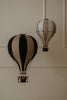 The Hot Air Balloon - Black, a decorative wooden model, hangs beautifully against a beige wall—an ideal handmade accent for children's room decor or as charming black balloon wall art.