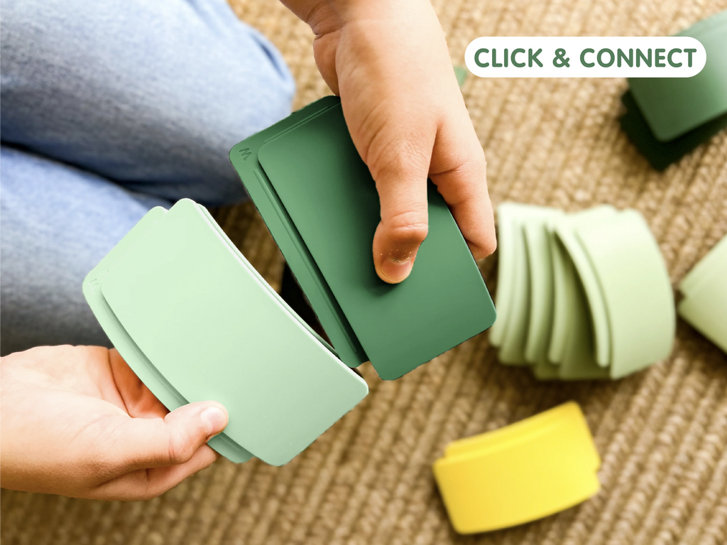 A person holds several green and light green curved plastic pieces, some scattered on a textured tan carpet. The WaytoPlay: Arches - Builder Set inspires imaginative play with endless building possibilities. The words “CLICK & CONNECT” appear in the top right corner.