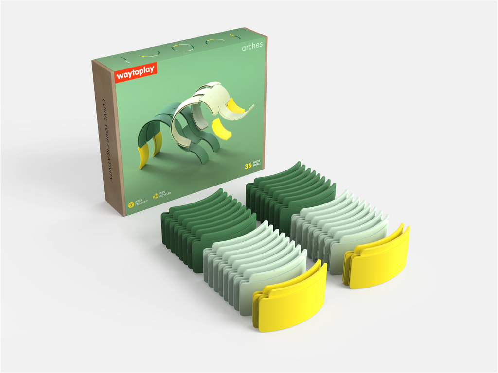 A box labeled “WaytoPlay: Arches - Creator Set” sits next to two rows of green and yellow curved toy pieces, arranged neatly on a white surface. This creative construction set inspires imaginative play and endless building possibilities.