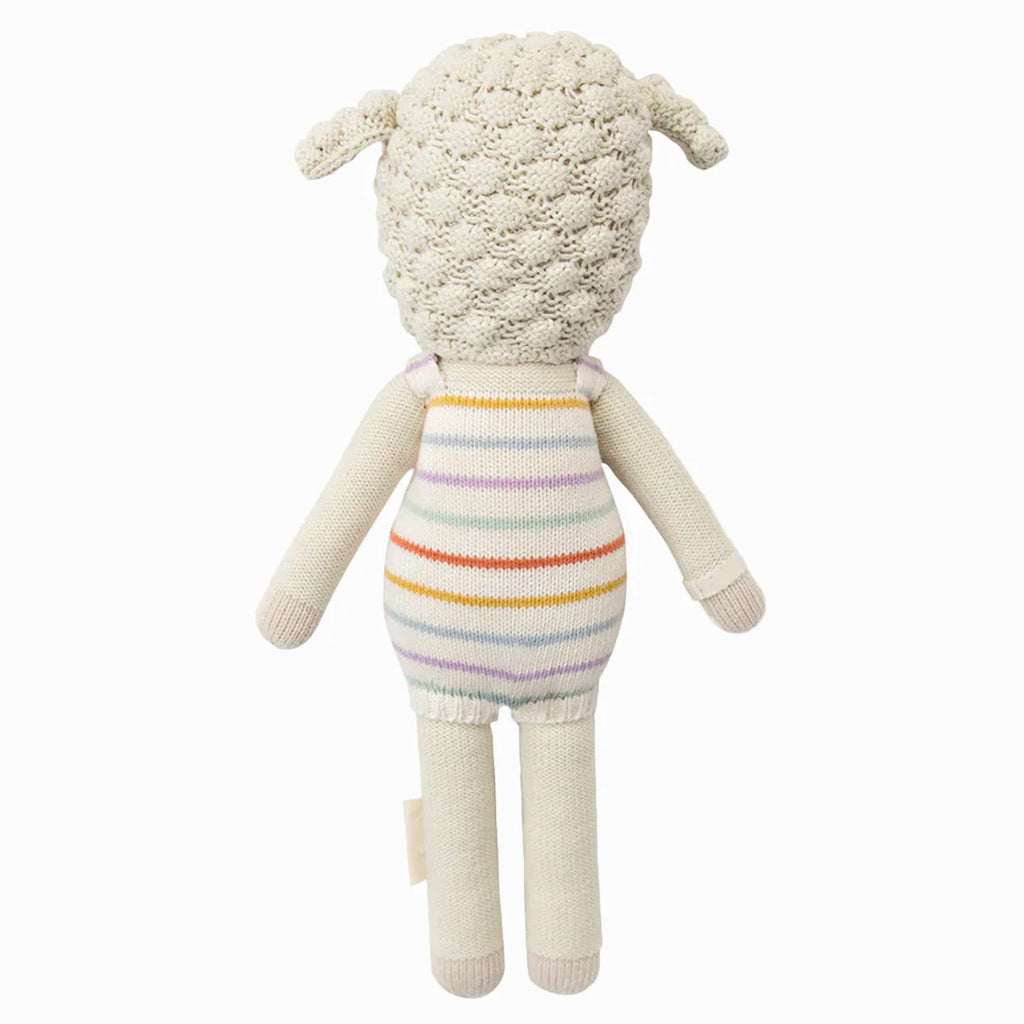 Cuddle + Kind Avery the Lamb is a hand-knit plush doll featuring textured cream wool, floppy ears, and a striped pastel romper. Made from 100% cotton yarn, it's shown from the back against a plain white background.