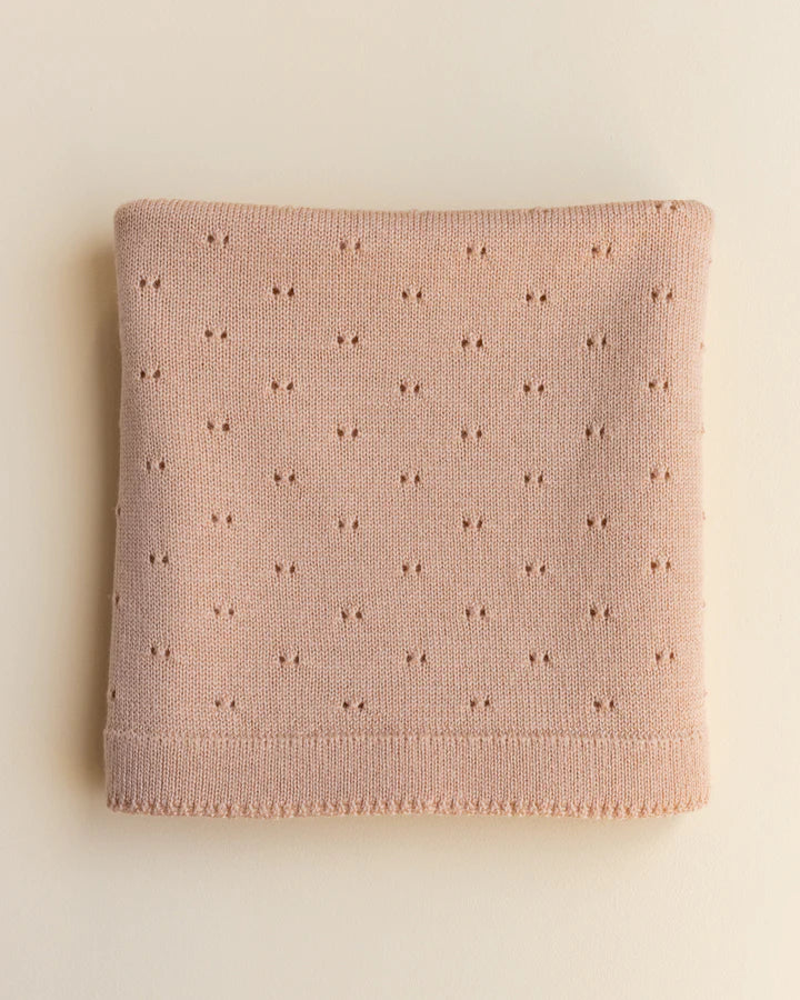 A folded apricot merino wool Bibi blanket with a delicate pattern of small, evenly spaced embroidered stars, displayed on a light beige background.