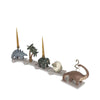 A whimsical 3D rendering showcasing a Dinosaur Birthday Train With Beeswax Candles, depicted as toys moving along a track with figures including a palm tree and mountains.