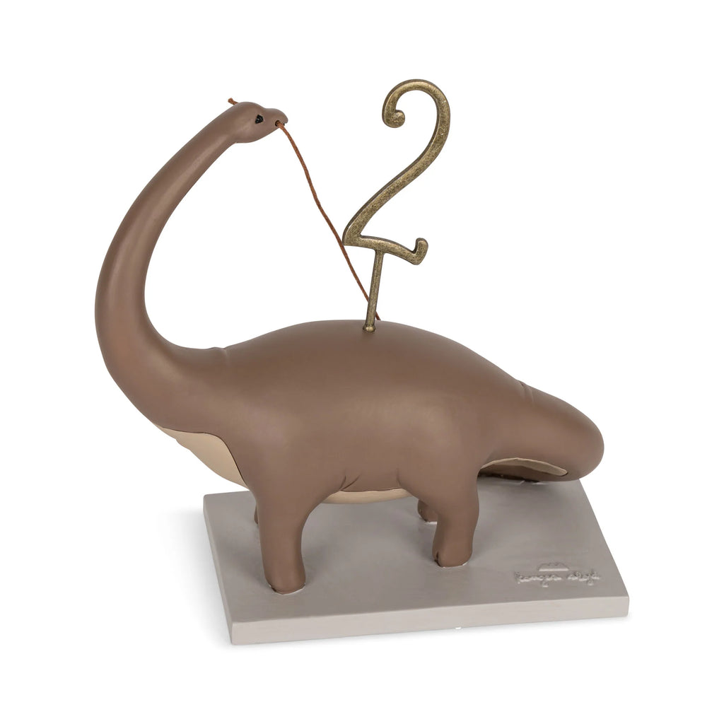 A whimsical statue of a brown brontosaurus playing a harp shaped like the number two, mounted on a gray platform, perfect for a Dinosaur Birthday Train With Beeswax Candles.