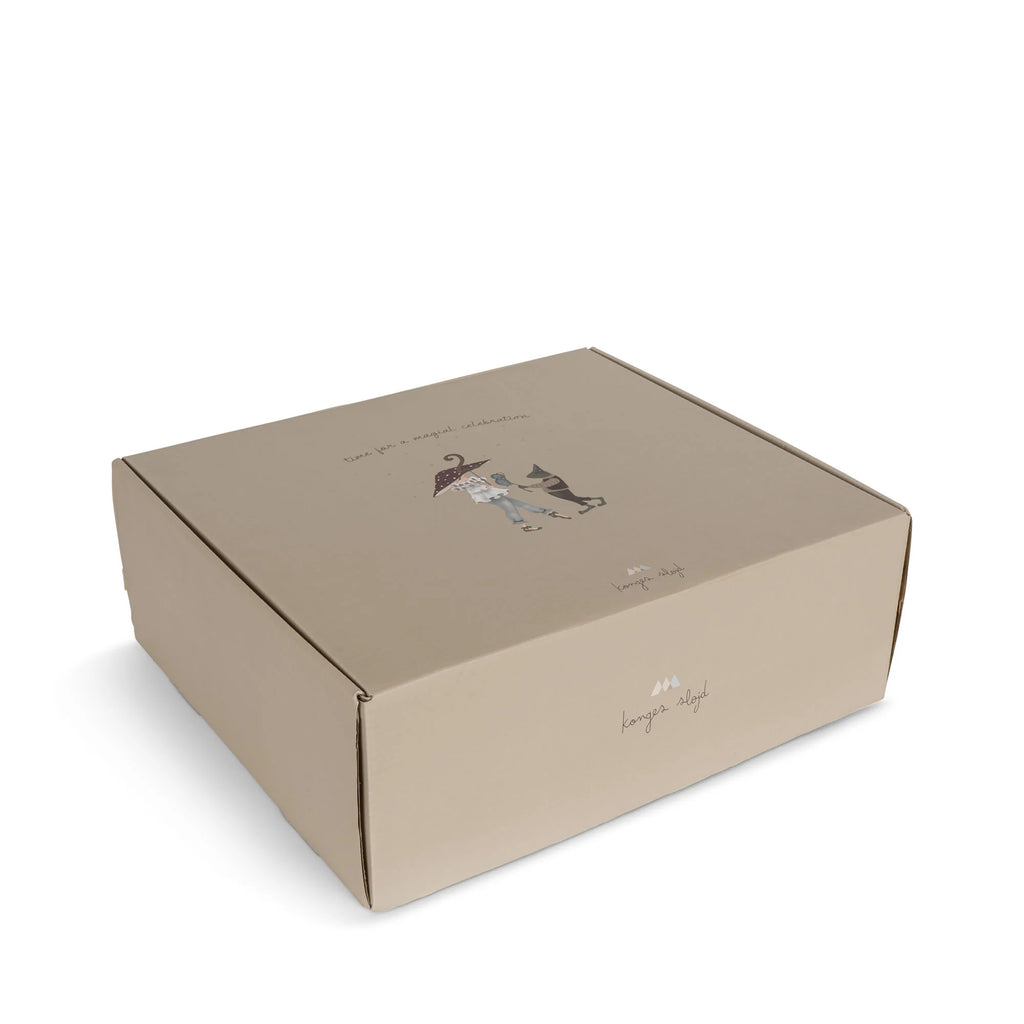 A rectangular, light brown cardboard box with simple illustrations and "konges sløjd" on the side, featuring a figure with an umbrella and a dog, designed for the Magical Forest Birthday Train With Beeswax Candles set.