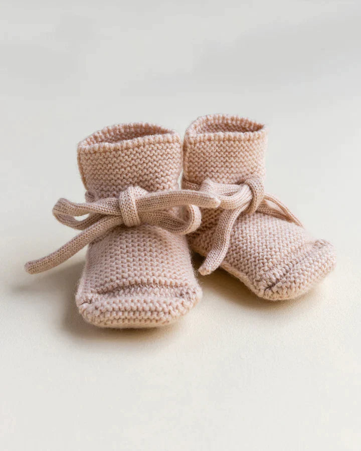 A pair of Handmade Merino Wool Booties in Apricot, made from merino wool, tied with delicate ribbons, set against a plain light background.