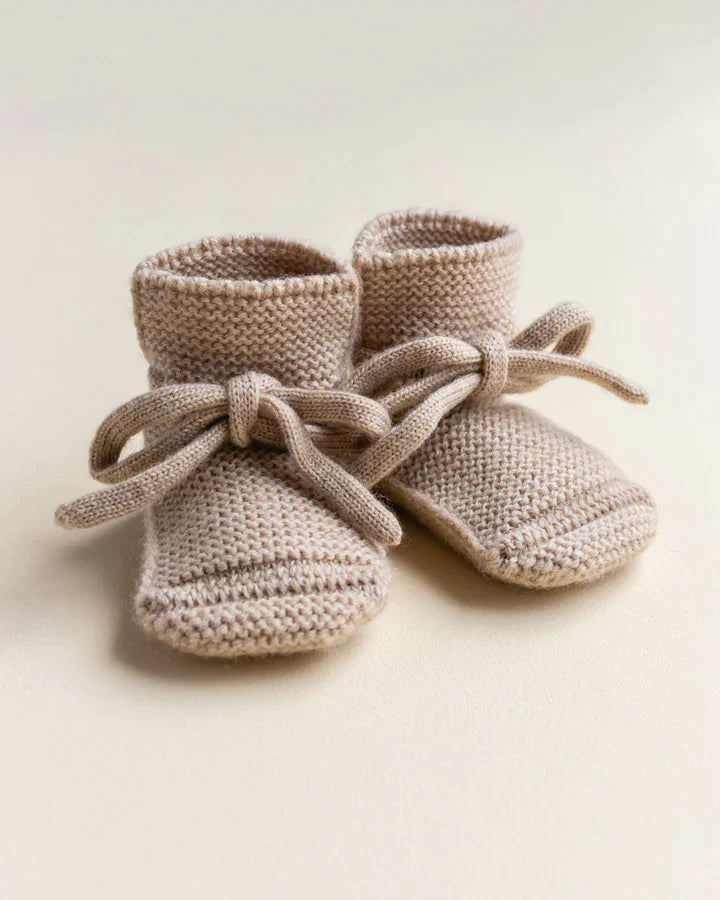 A pair of Handmade Merino Wool Booties in Sand, ideal for sensitive skin, with ties, displayed on a plain light background.