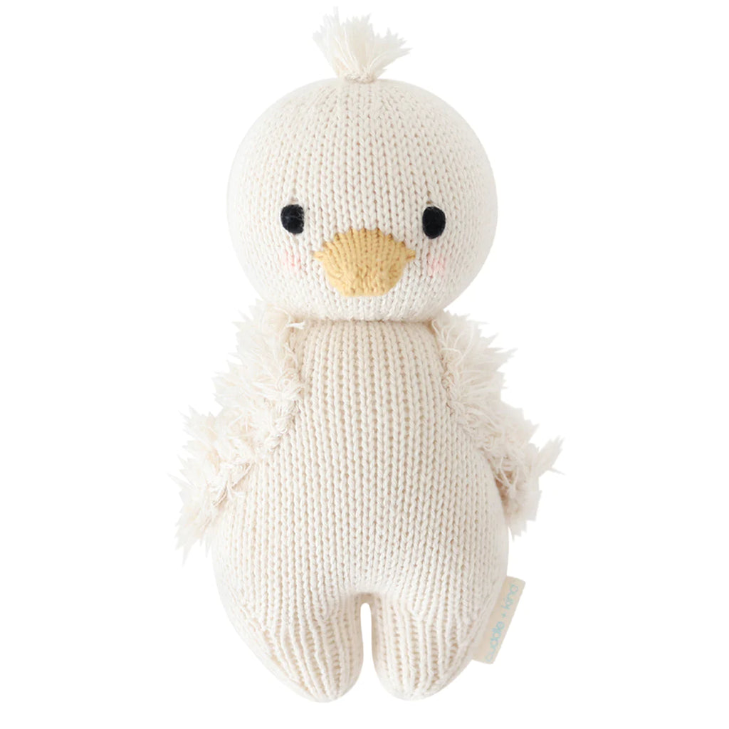 A Cuddle + Kind Baby Gosling plush toy depicting a cute, hand-knit chick with a fluffy texture, an orange beak, and a tuft of white hair on top, sitting upright against a white background.