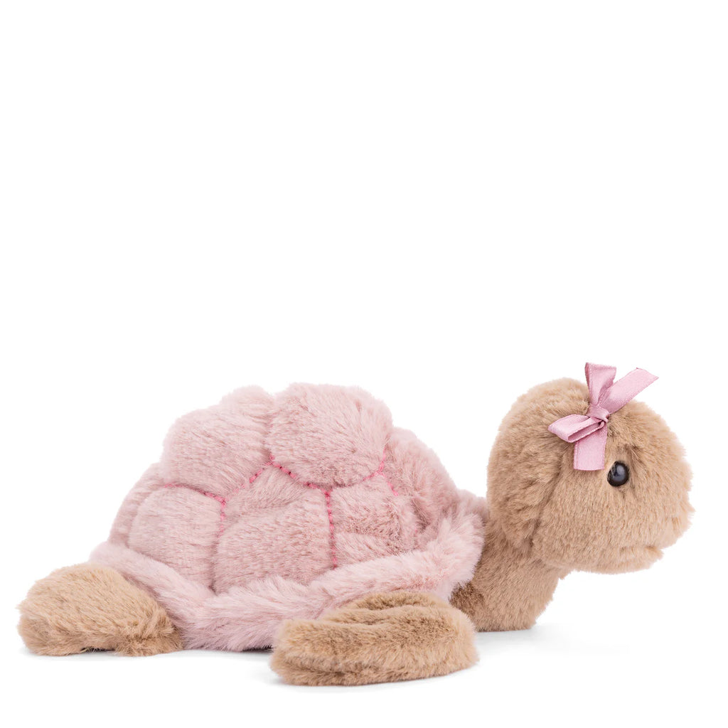 The Bukowski Baby Sandy Sea Turtle - Pink is a plush toy featuring a soft pink shell, light brown body, and a pink bow on its head. The adorable sea turtle is shown facing right against a white background.