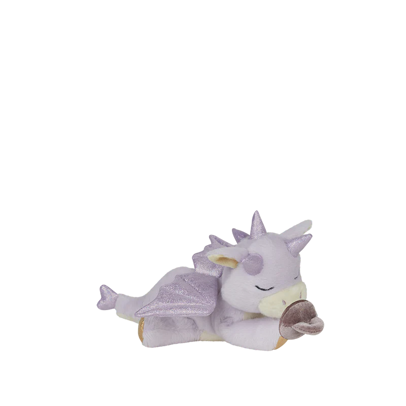 The Olli Ella Binky Dragon - Misty - Lavender is a light purple plush dragon with glittery wings, pale accents, closed eyes, and a small brown magnetic pacifier in its arms, shown lying down against a white background.