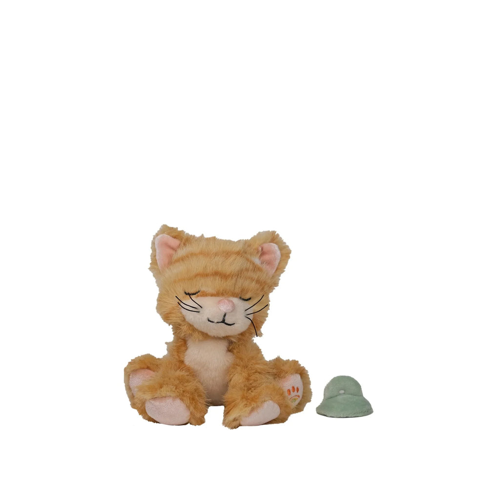 An Olli Ella Binky Kitten Koda - Ginger plush toy with closed eyes sits upright beside a small green hat on a plain white background.