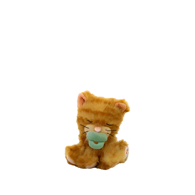 The Olli Ella Binky Kitten Koda - Ginger, a plush orange kitten with closed eyes and a magnetic pacifier toy in its mouth, sits on a plain white background.